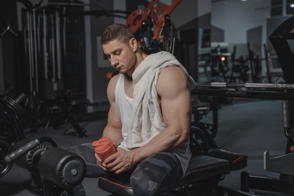 mężczyzna na siłowni ze shakiem proteinowym