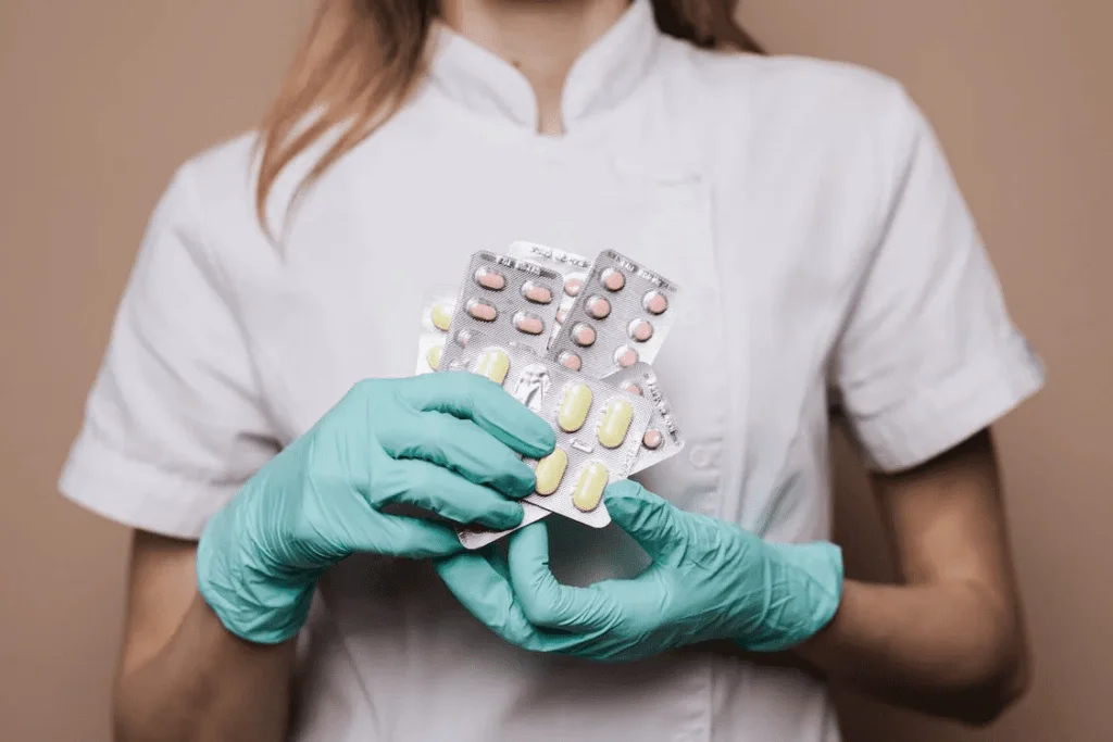 kobieta trzymająca blistery z tabletkami i kapsułkami